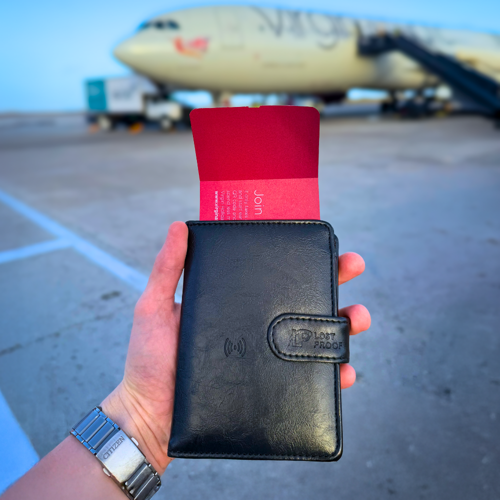Hand holding a black CardPass™ wallet with a red boarding pass in front of a virgin airplane on a runway.