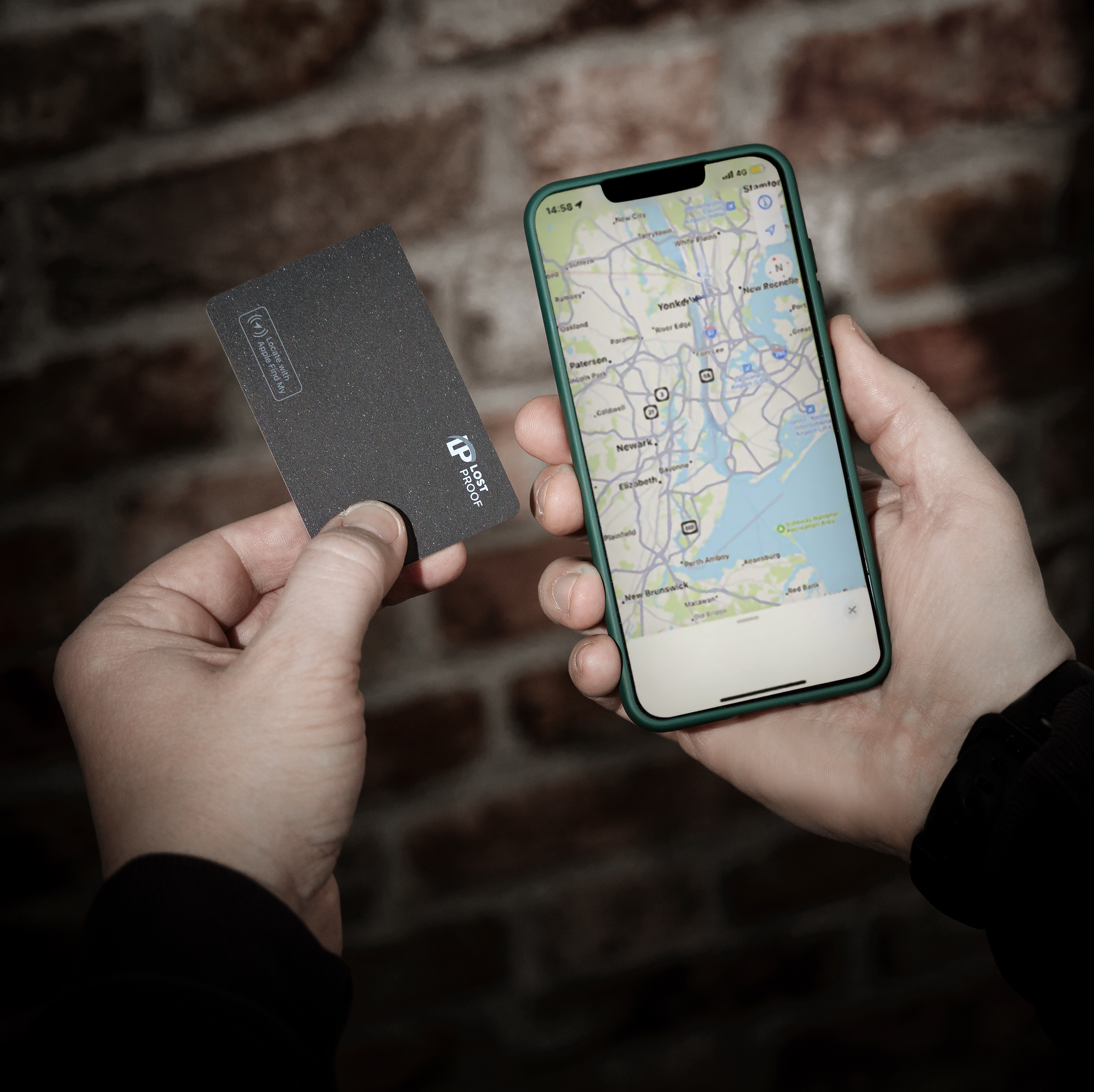 A person holding a LostProof CardTrack wallet tracker in one hand and an iPhone displaying the Apple Find My app in the other. The tracker is sleek and black, designed to fit inside a wallet for easy location tracking.